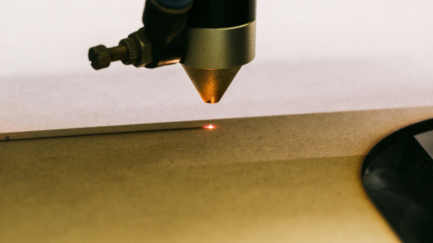 Laser engraver beam burning design into wood.