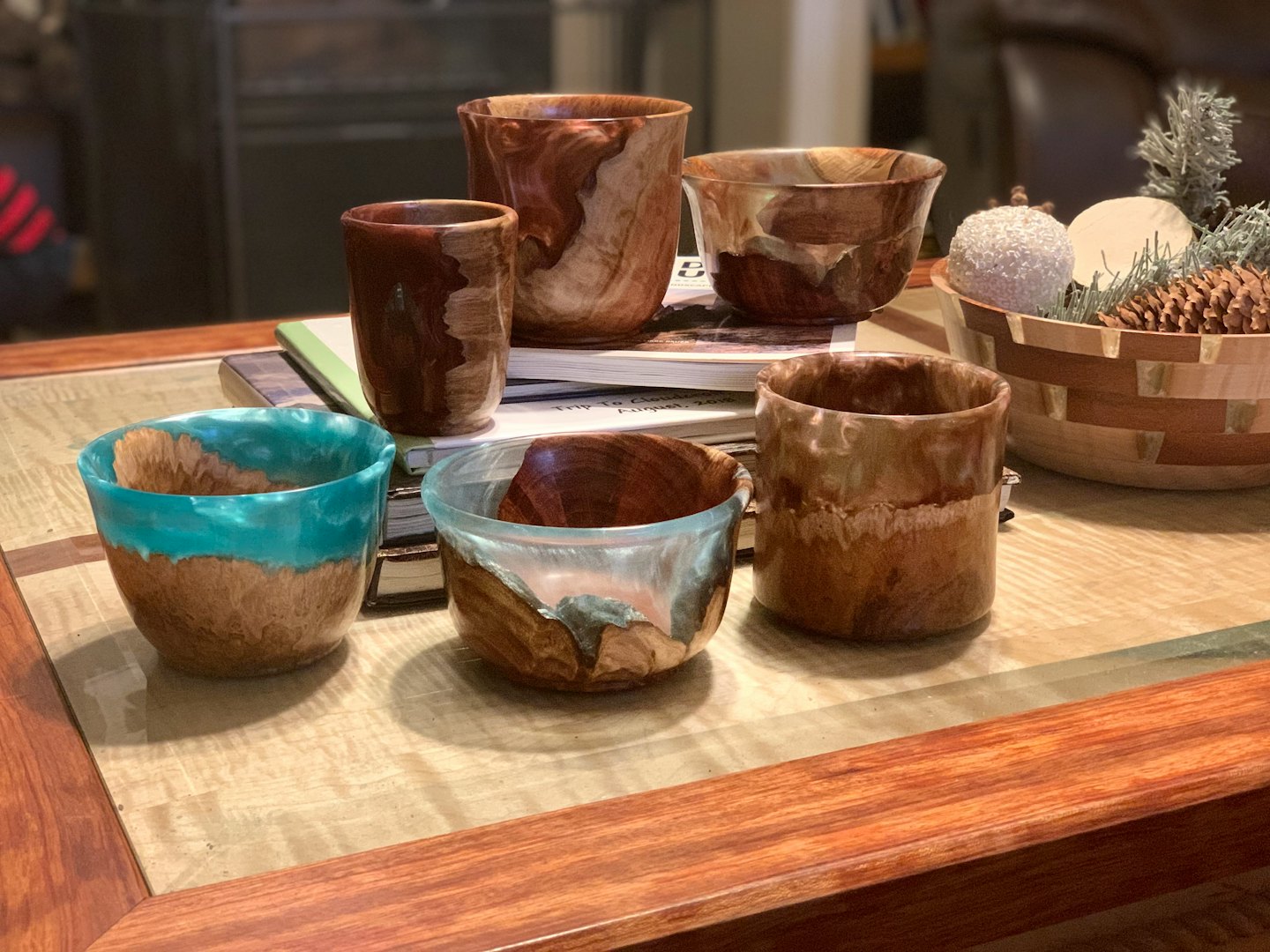 Handmade wooden bowls and cups arranged on a wooden table.